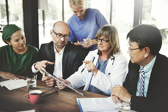 Five medical professionals talk together during a meeting.