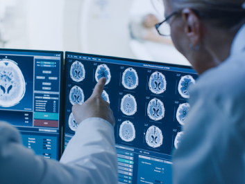 2 doctors looking at a screen of brain scans