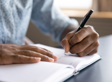 Men holding a pen writing on a notebook