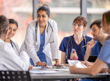 Medical professionals having a meeting in a private room sitting at a desk. 