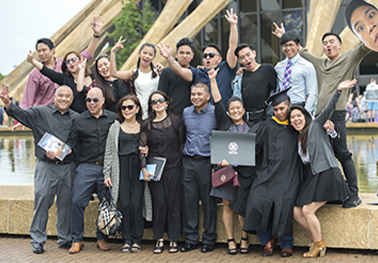 More than a dozen family members enthusiastically pose with a graduate in front of Norfolk Scope