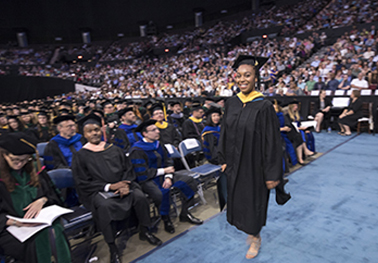 A Black female graduate walks the stage at Norfolk Scope