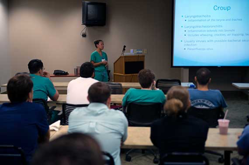 Students facing an instructor in rows of tables