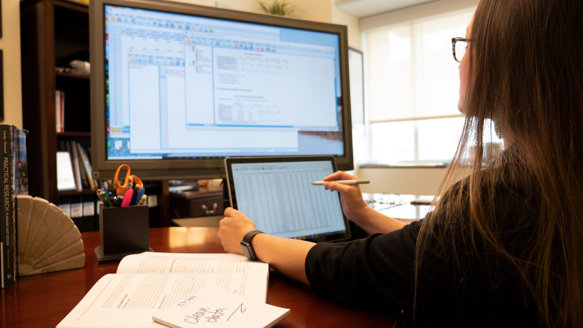 Camera looks over the shoulder of a MHPE student sitting at a computer monitor