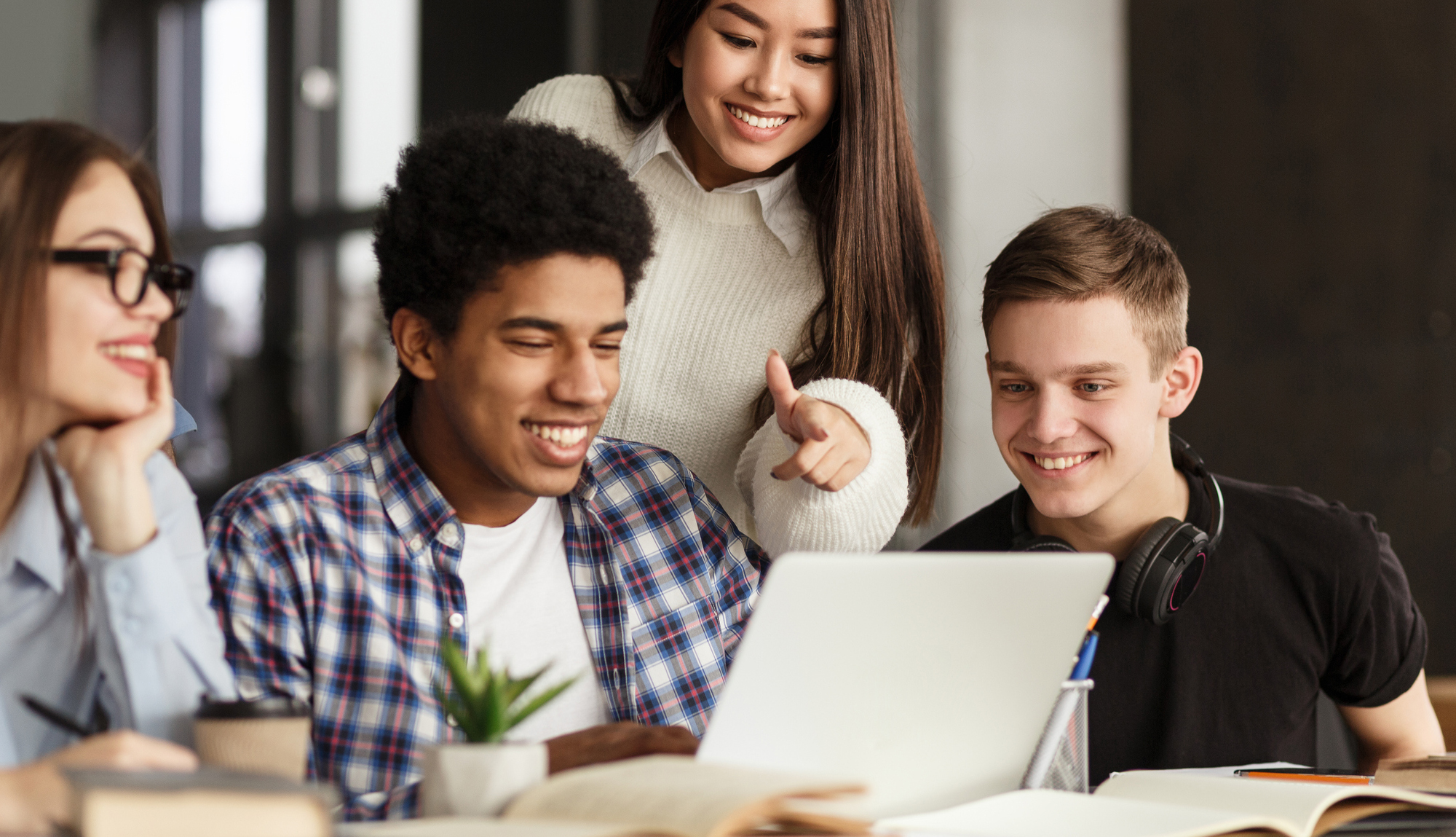 A diverse group of students huddle around a computer