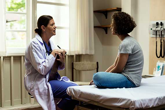 A physician talks with a patient in an exam room.