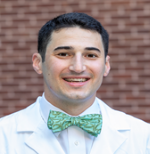 Maxwell Wagner, MD, smiles at the camera in his white coat